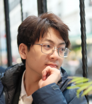 Photograph of Jerry Tian. He is wearing glasses and a grey jacket. He is looking down and to the side, away from the camera.